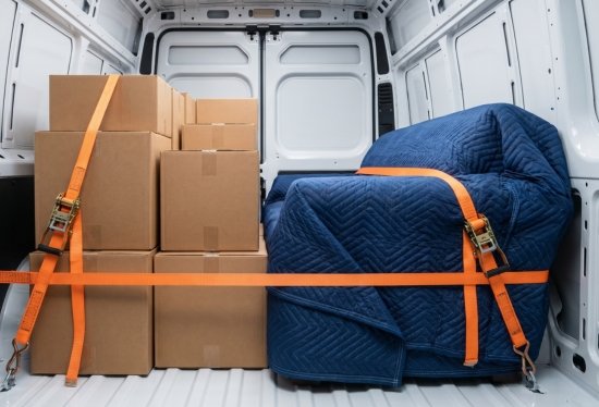 Close-up inside the moving van showing furniture and boxes securely strapped and wrapped in premium transit blankets for a long-distance haul.