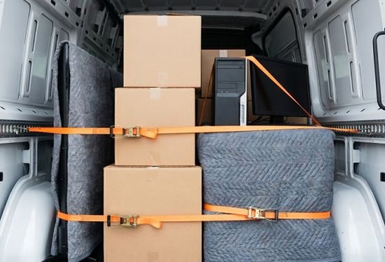 Close up inside the moving van showing student boxes and belongings securely strapped and blanket-wrapped for safe transport.
