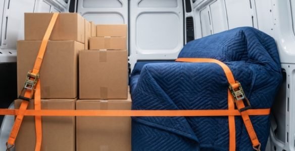 Close-up inside the moving van showing furniture and boxes securely strapped and wrapped in premium transit blankets for a long-distance haul.